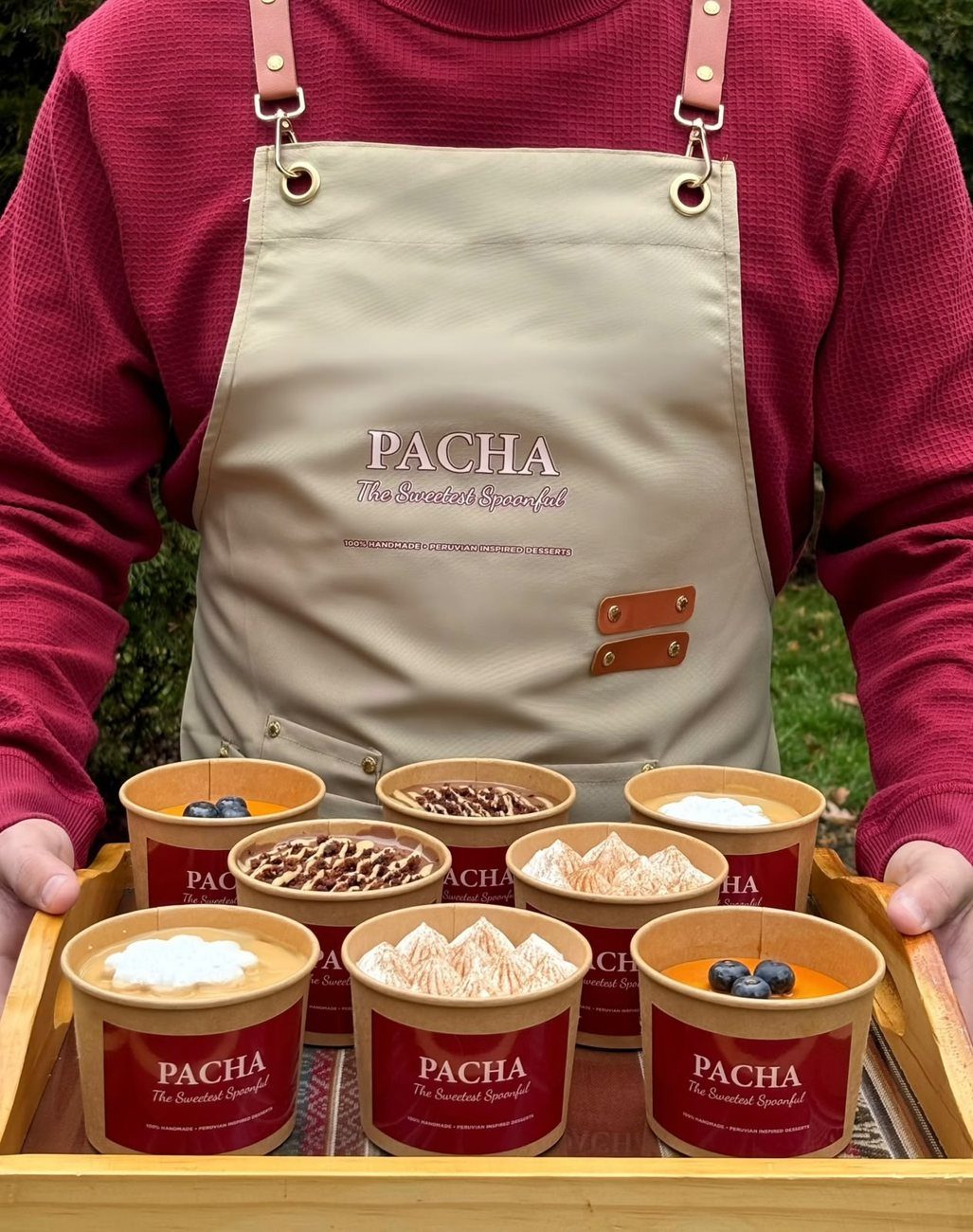 A tray of PACHA spoonable desserts in front of a PACHA apron